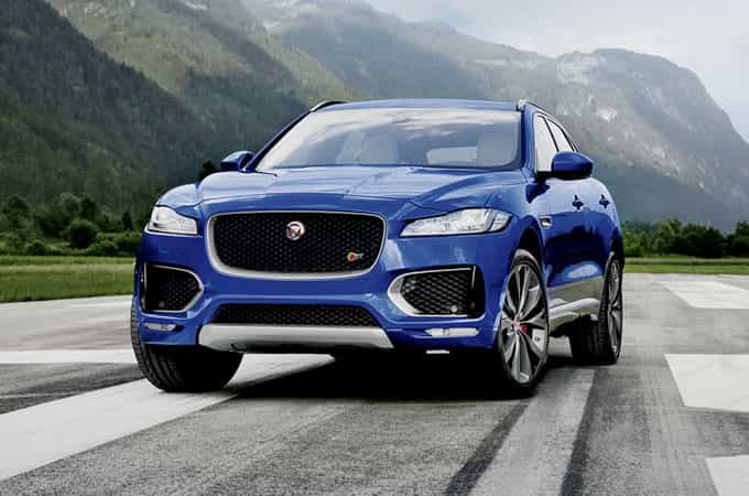 The Jaguar F-PACE parked on a strip of tarmac, in front of hills. 